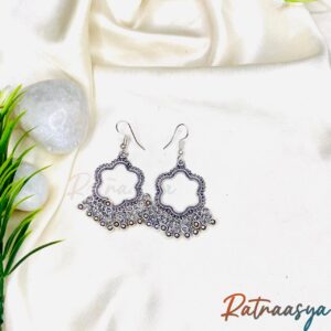 Quatrefoil oxidized silver dangler earrings with beaded accents on white background