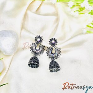 Peacock motif oxidized silver jhumka earrings with floral tops and sparkling stones on white background