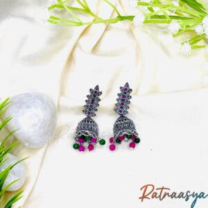 Leafy stone oxidized silver jhumka earrings with pink and green accents and hanging colored beads on white background