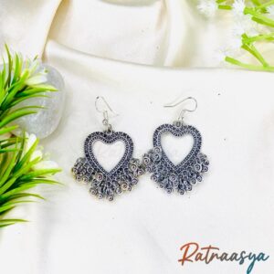 Heart motif oxidized silver dangler earrings with detailed work and hanging beads on white background