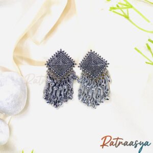 Tribal kite-shaped oxidized silver dangler earrings with intricate design and metallic fringe on white background